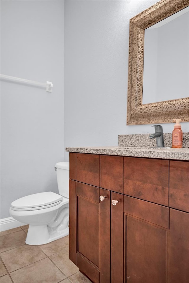 half bath with tile patterned flooring, vanity, and toilet