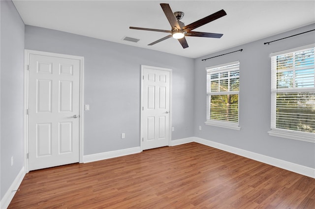 unfurnished bedroom featuring wood finished floors, visible vents, and baseboards