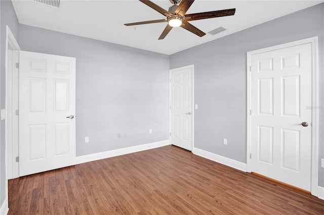 unfurnished bedroom with baseboards, visible vents, dark wood finished floors, and a ceiling fan