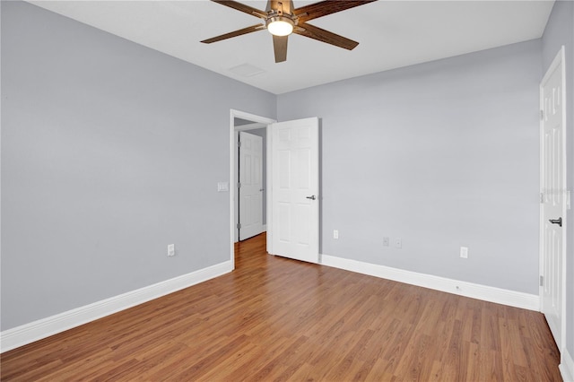 empty room with ceiling fan, wood finished floors, and baseboards