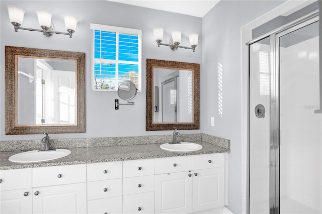 bathroom with a sink, a shower stall, and double vanity