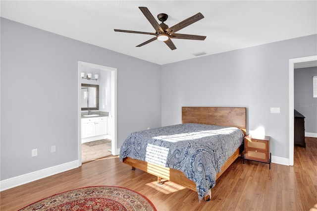 bedroom with visible vents, connected bathroom, ceiling fan, wood finished floors, and baseboards