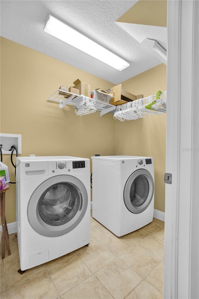 washroom featuring a textured ceiling, laundry area, light tile patterned floors, and washing machine and dryer