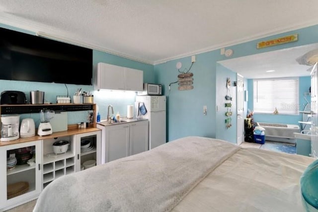 bedroom featuring freestanding refrigerator, a sink, and crown molding