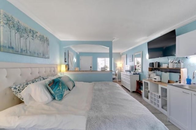 bedroom featuring light tile patterned floors, a sink, arched walkways, and crown molding