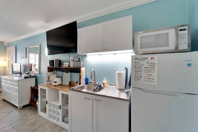 kitchen featuring white cabinets, a sink, crown molding, and white appliances