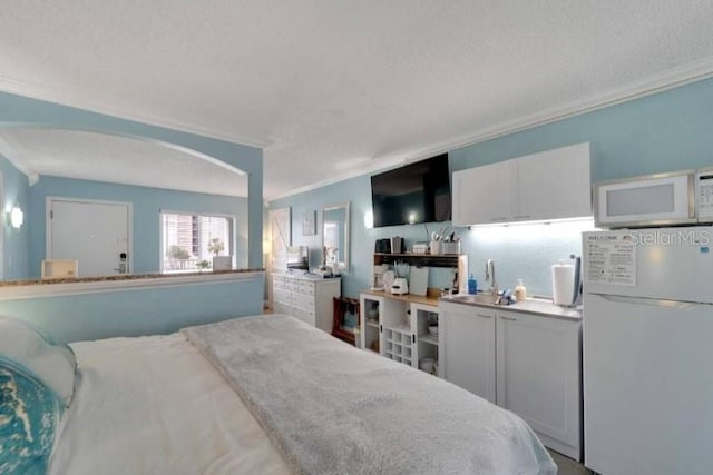 bedroom featuring arched walkways, a textured ceiling, crown molding, and freestanding refrigerator