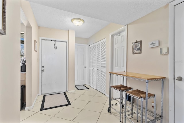 entrance foyer featuring baseboards, a textured ceiling, and light tile patterned flooring