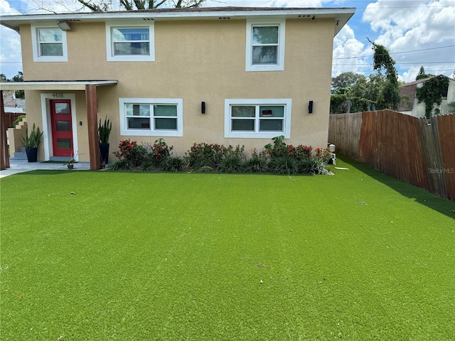 view of front facade featuring a front yard, fence, and stucco siding