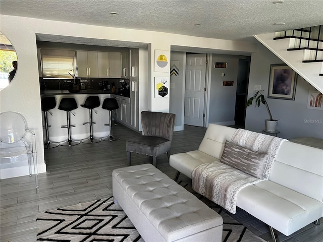 living room featuring stairway, a textured ceiling, and wood finished floors