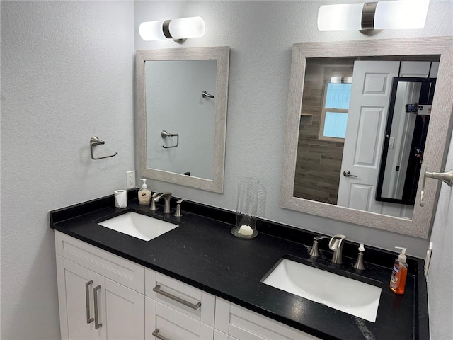 bathroom featuring a textured wall, double vanity, and a sink