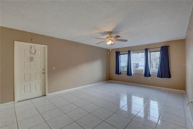 unfurnished room with ceiling fan, a textured ceiling, baseboards, and light tile patterned floors