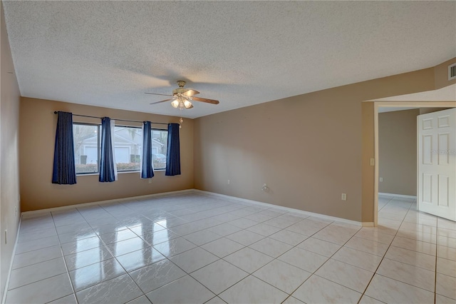 spare room featuring light tile patterned floors, visible vents, a ceiling fan, a textured ceiling, and baseboards