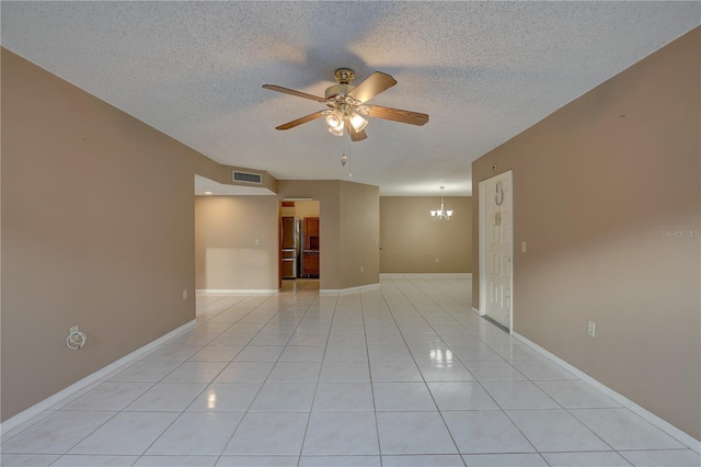 empty room featuring visible vents, light tile patterned flooring, a textured ceiling, baseboards, and ceiling fan with notable chandelier