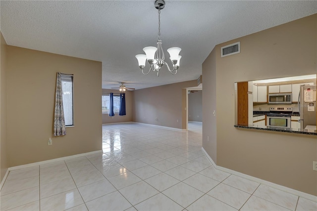 empty room with light tile patterned floors, a textured ceiling, ceiling fan with notable chandelier, visible vents, and baseboards