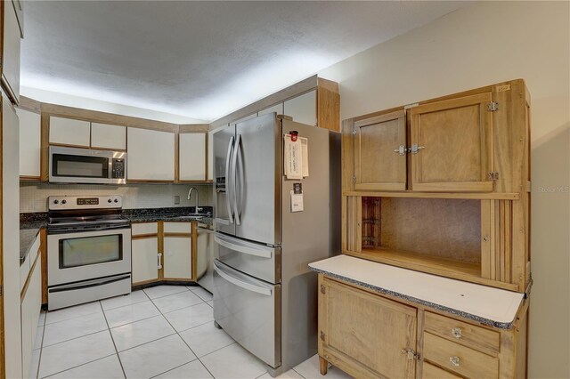 kitchen with light tile patterned floors, appliances with stainless steel finishes, a sink, and tasteful backsplash