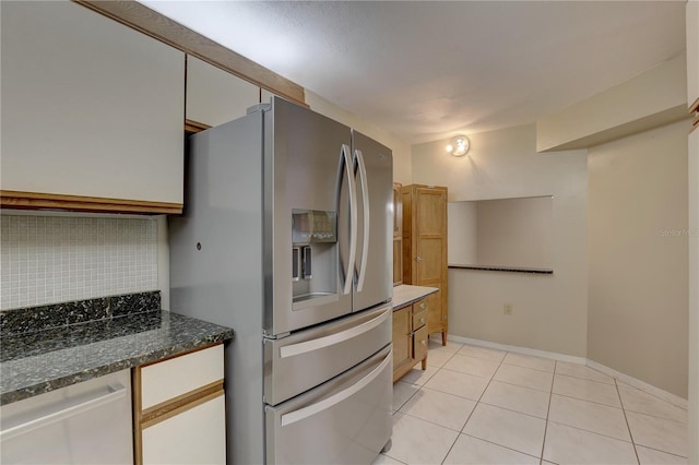 kitchen with light tile patterned floors, dishwashing machine, baseboards, decorative backsplash, and stainless steel fridge