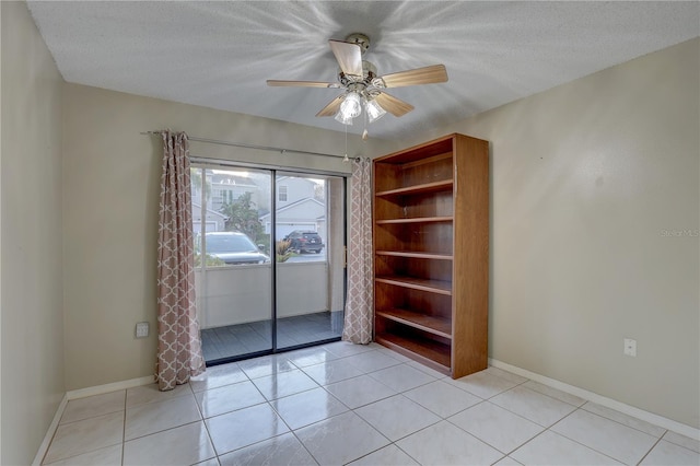 spare room featuring ceiling fan, baseboards, a textured ceiling, and light tile patterned flooring