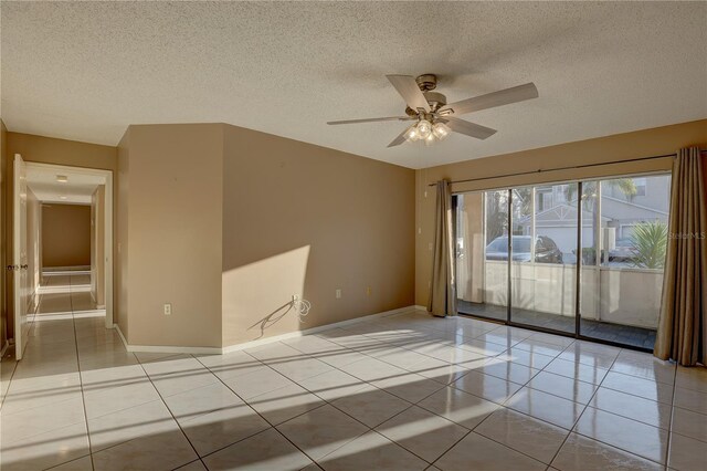 spare room with light tile patterned floors, a ceiling fan, baseboards, and a textured ceiling