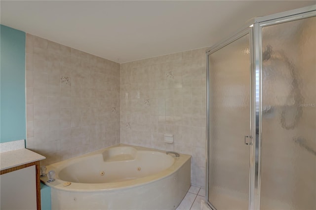 bathroom with a stall shower, a whirlpool tub, tile patterned flooring, vanity, and tile walls