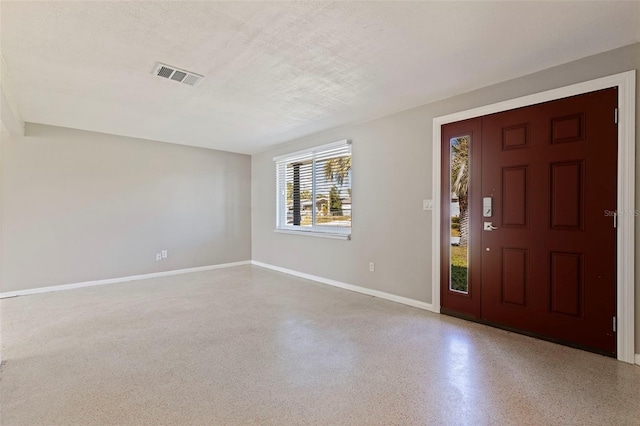 entrance foyer with a textured ceiling, speckled floor, visible vents, and baseboards