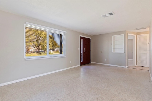 spare room with light speckled floor, visible vents, and baseboards