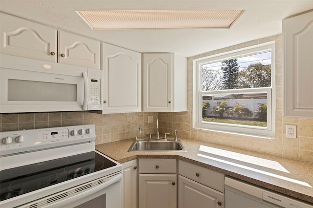 kitchen featuring tasteful backsplash, white appliances, white cabinetry, and a sink