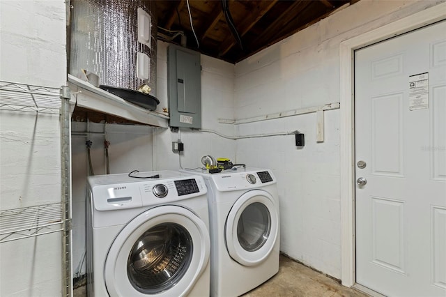 washroom featuring concrete block wall, laundry area, washing machine and dryer, and electric panel