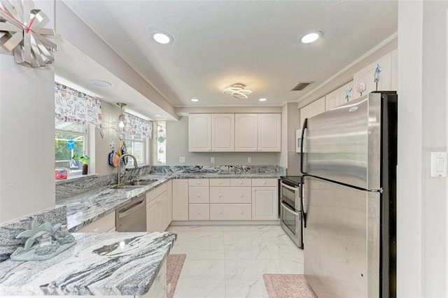 kitchen with marble finish floor, recessed lighting, appliances with stainless steel finishes, a sink, and light stone countertops