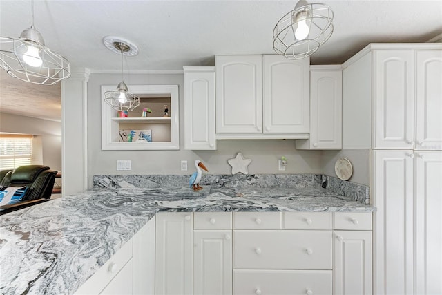 kitchen with light stone counters, white cabinets, and pendant lighting