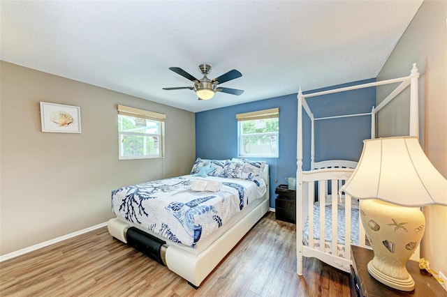 bedroom featuring multiple windows, wood finished floors, and baseboards