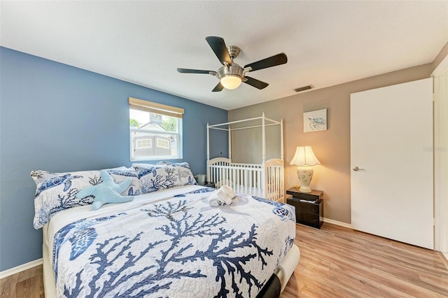 bedroom with baseboards, visible vents, a ceiling fan, a textured ceiling, and light wood-type flooring