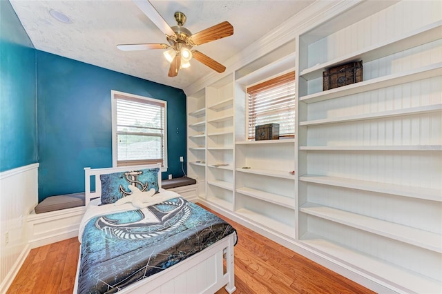 bedroom featuring light wood-type flooring, ceiling fan, and a textured ceiling