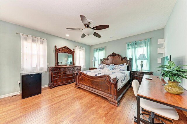 bedroom featuring a ceiling fan, light wood-style flooring, and baseboards