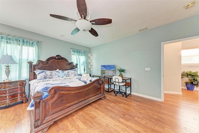 bedroom with multiple windows, wood finished floors, visible vents, and baseboards