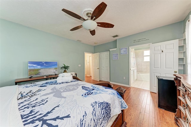 bedroom with visible vents, a textured ceiling, ensuite bath, light wood-type flooring, and baseboards