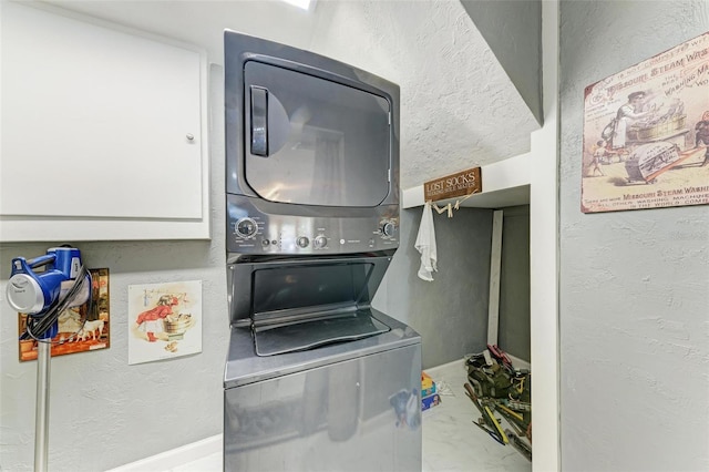 laundry room featuring laundry area, stacked washer / dryer, and a textured wall