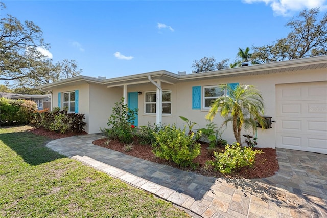 ranch-style house featuring an attached garage, a front yard, and stucco siding