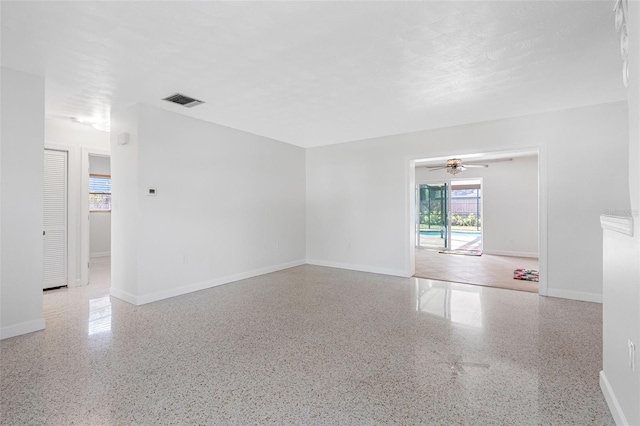 empty room featuring visible vents, baseboards, and speckled floor