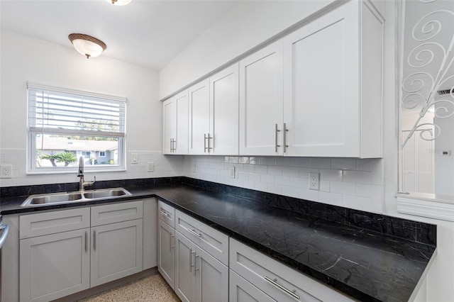 kitchen with light speckled floor, backsplash, a sink, and white cabinets