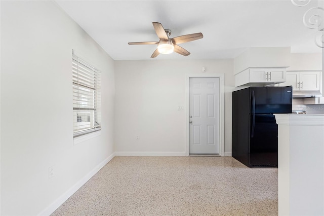 kitchen with freestanding refrigerator, white cabinetry, ceiling fan, under cabinet range hood, and baseboards