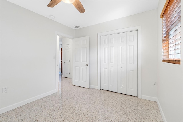 unfurnished bedroom featuring speckled floor, a closet, and baseboards