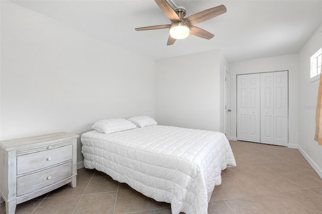 bedroom with light tile patterned floors, a closet, a ceiling fan, and baseboards