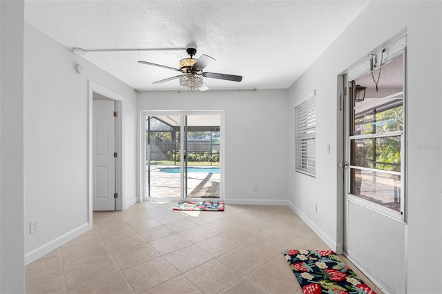 empty room featuring a textured ceiling, baseboards, and light tile patterned floors