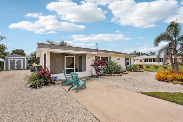 exterior space with a patio, a storage shed, an outdoor structure, a sunroom, and stucco siding