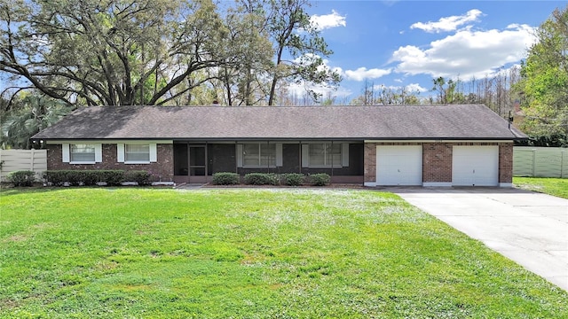 ranch-style home featuring an attached garage, brick siding, fence, concrete driveway, and a front yard