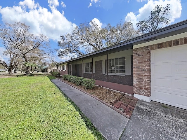 view of side of property with a garage, brick siding, and a yard