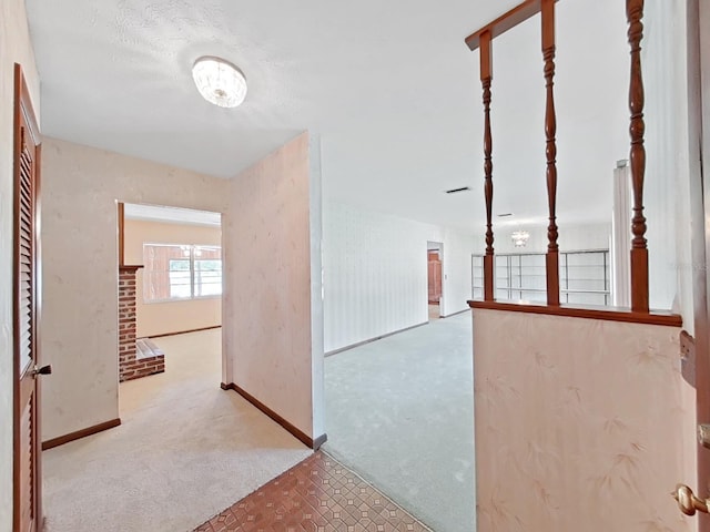 corridor with light colored carpet, visible vents, and baseboards