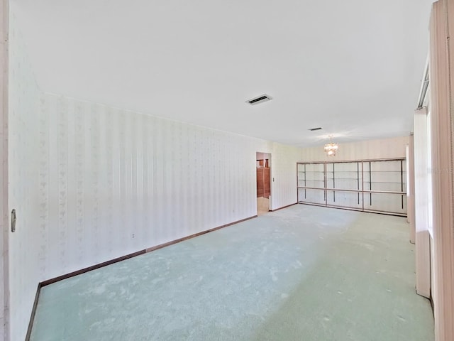 empty room featuring wallpapered walls, baseboards, visible vents, and a chandelier