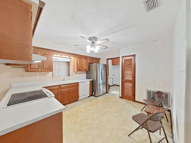 kitchen featuring light countertops, freestanding refrigerator, a sink, dishwasher, and under cabinet range hood